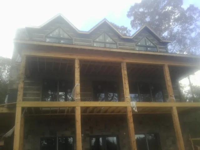 Dormers and porch framing on a large log home under construction — Roof Coating work by our crew in Buffalo Grove