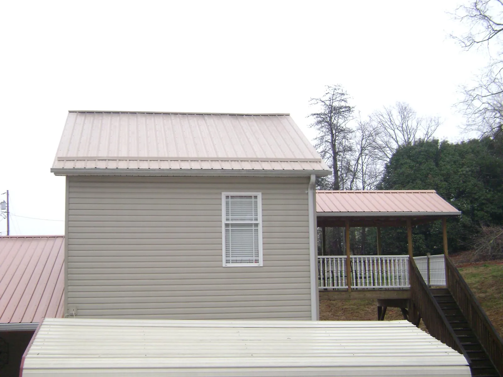 Tan metal roofs on a two story addition and attached porch, from a Roof Replacement job in Buffalo Grove
