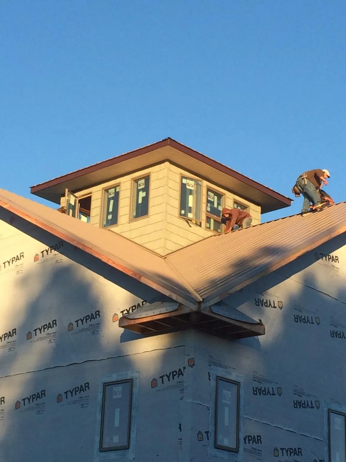 Roofers working around a rooftop cupola on a new metal roof at sunset — Roof Waterproofing in Buffalo Grove by Roofing Brothers